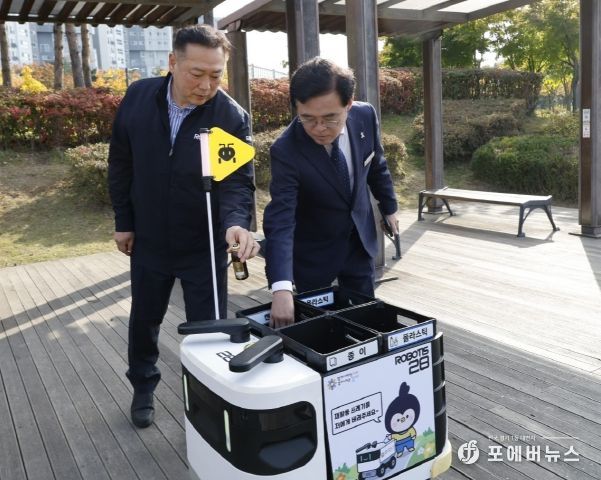진교훈 서울 강서구청장(오른쪽)이 마곡하늬공원에서 열린 ‘AI 기반 자율주행 로봇서비스 실증 시연회’에서 빈 캔을 수거함에 넣고 있다.