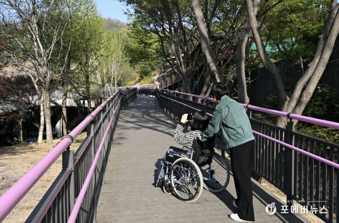 휠체어 이용객이 무장애 데크길을 이용해 진달래동산으로 이동하고 있다.